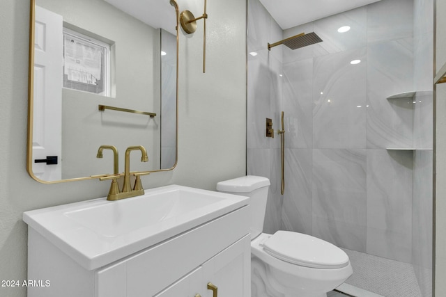 bathroom with a tile shower, vanity, and toilet