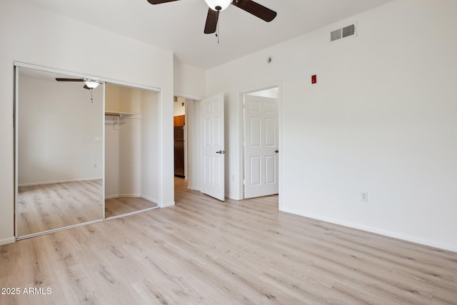unfurnished bedroom with a ceiling fan, visible vents, wood finished floors, baseboards, and a closet