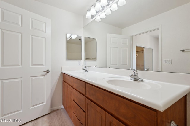 bathroom with double vanity, baseboards, a sink, and wood finished floors