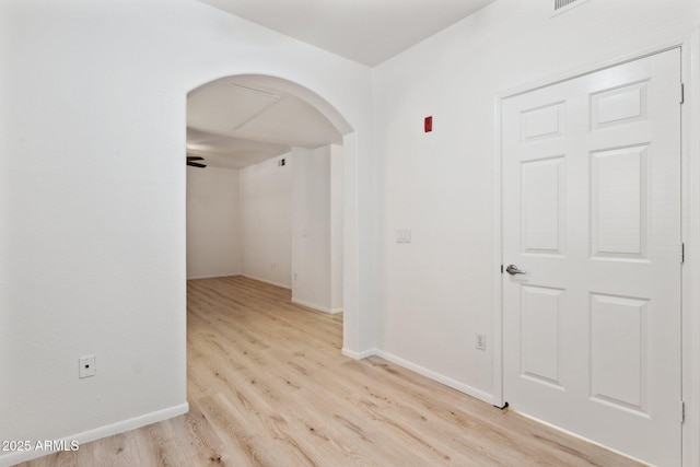 unfurnished room with arched walkways, baseboards, and wood finished floors