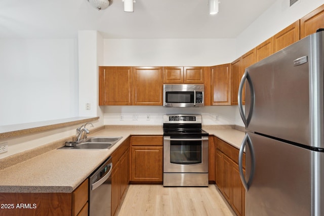 kitchen with stainless steel appliances, brown cabinetry, and a sink