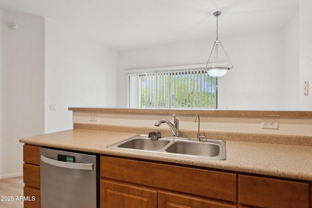kitchen with stainless steel dishwasher, a sink, brown cabinetry, and light countertops