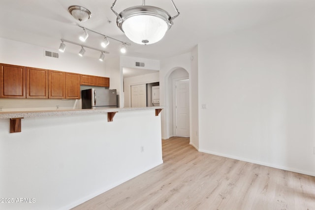 kitchen featuring visible vents, freestanding refrigerator, light countertops, and a kitchen bar