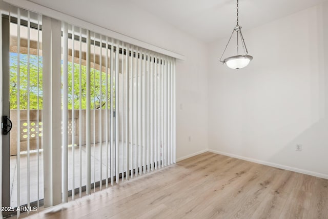 spare room with baseboards and wood finished floors