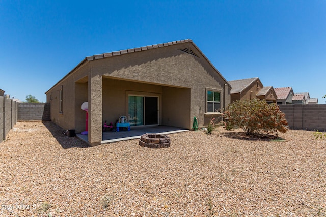 rear view of house with a fire pit and a patio