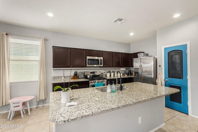 kitchen featuring light stone counters, sink, a kitchen island with sink, and appliances with stainless steel finishes