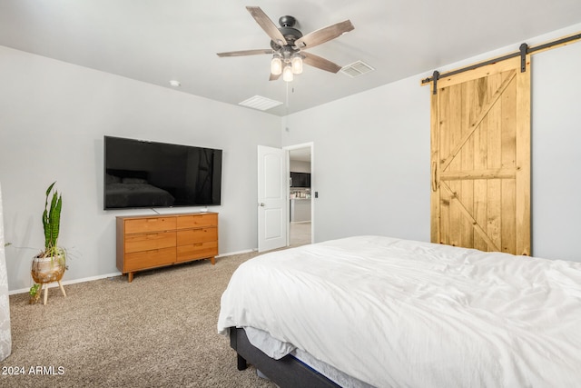 bedroom featuring a barn door, ceiling fan, and carpet floors