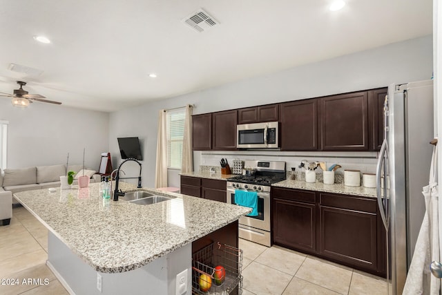 kitchen with light stone countertops, a center island with sink, stainless steel appliances, and sink