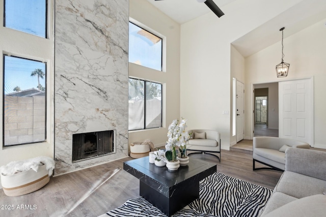living room with a towering ceiling, wood finished floors, a high end fireplace, and baseboards