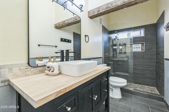 bathroom featuring tiled shower, toilet, and vanity