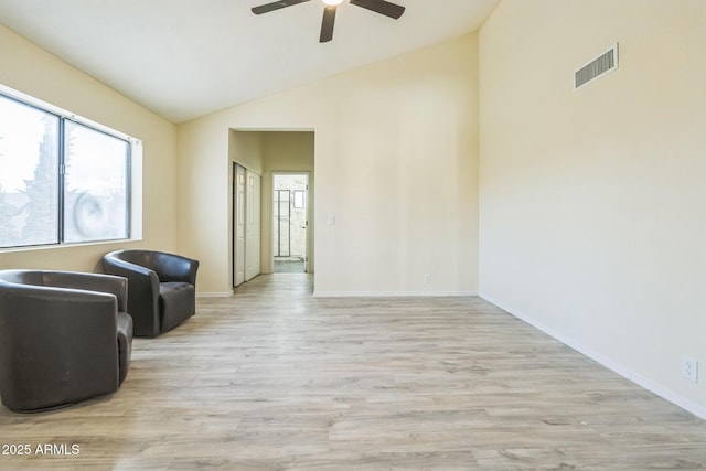 living area featuring ceiling fan, light wood-type flooring, baseboards, and high vaulted ceiling