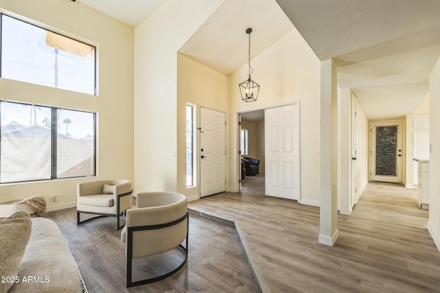 living room featuring baseboards, high vaulted ceiling, and wood finished floors