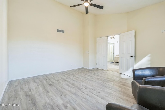 living area featuring ceiling fan, wood finished floors, high vaulted ceiling, and baseboards
