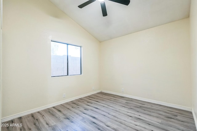 empty room featuring ceiling fan, wood finished floors, baseboards, and vaulted ceiling