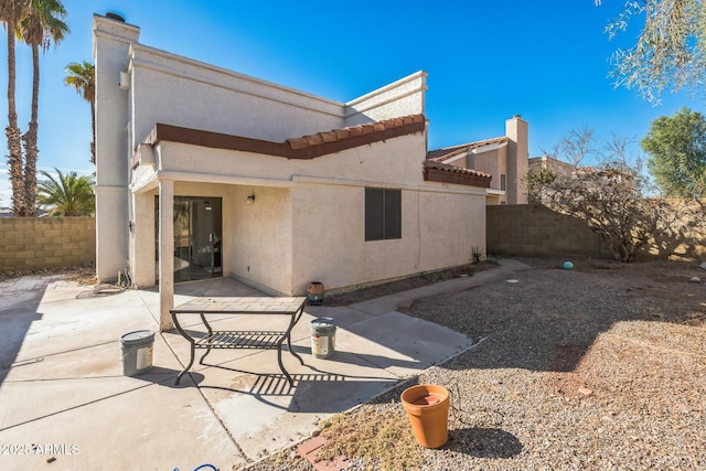 back of house with stucco siding, a fenced backyard, a chimney, and a patio