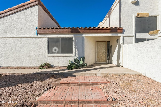 property entrance featuring stucco siding and a tiled roof