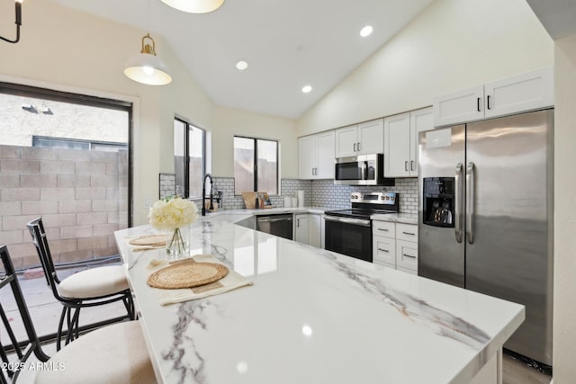 kitchen featuring appliances with stainless steel finishes, a sink, light stone countertops, white cabinetry, and backsplash