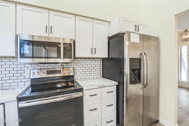 kitchen with stainless steel appliances, light countertops, backsplash, and white cabinetry