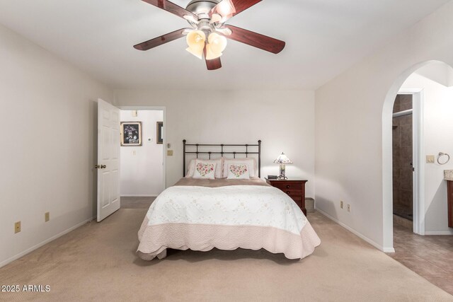 bedroom featuring a ceiling fan, arched walkways, baseboards, and light carpet