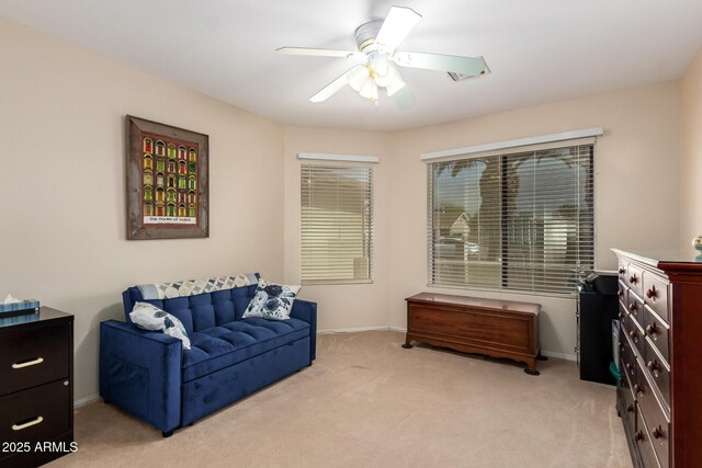 sitting room featuring baseboards, a ceiling fan, and light colored carpet