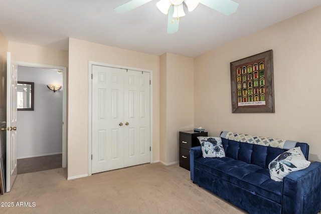living area with baseboards, ceiling fan, and light colored carpet