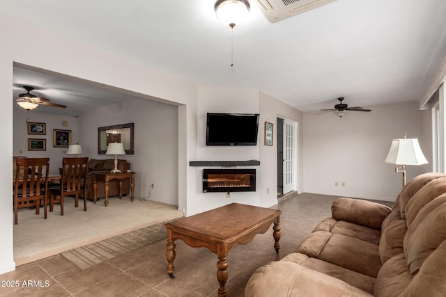 living room with carpet flooring, ceiling fan, visible vents, and a glass covered fireplace