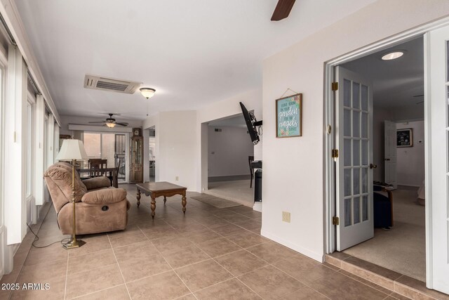 living area with baseboards, visible vents, light tile patterned floors, and a ceiling fan
