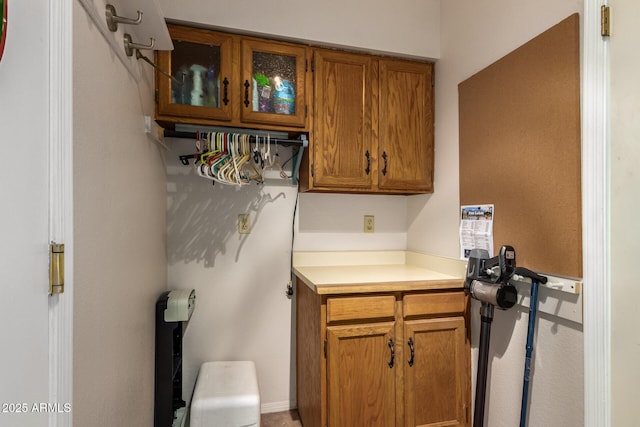 interior space with glass insert cabinets, light countertops, and brown cabinets