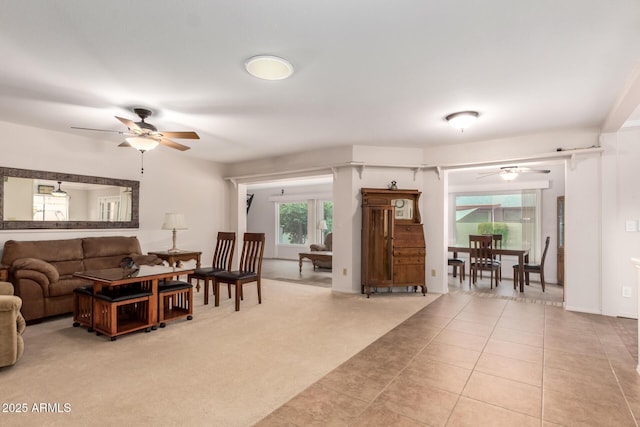 living room featuring light tile patterned flooring, light colored carpet, and a ceiling fan