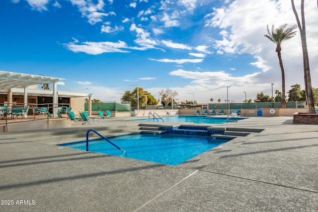 community pool with a hot tub, a pergola, fence, and a patio