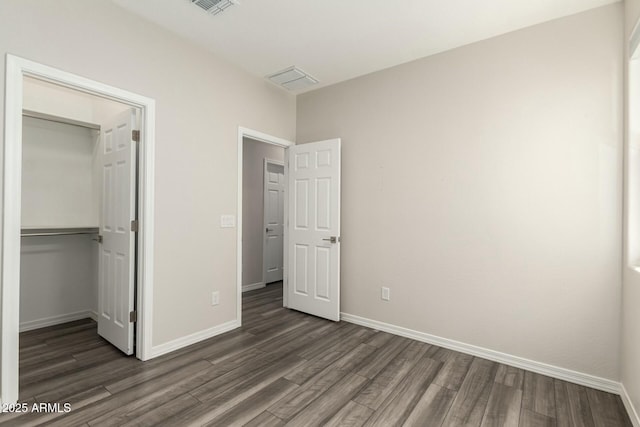 unfurnished bedroom featuring a closet, baseboards, dark wood-type flooring, and visible vents