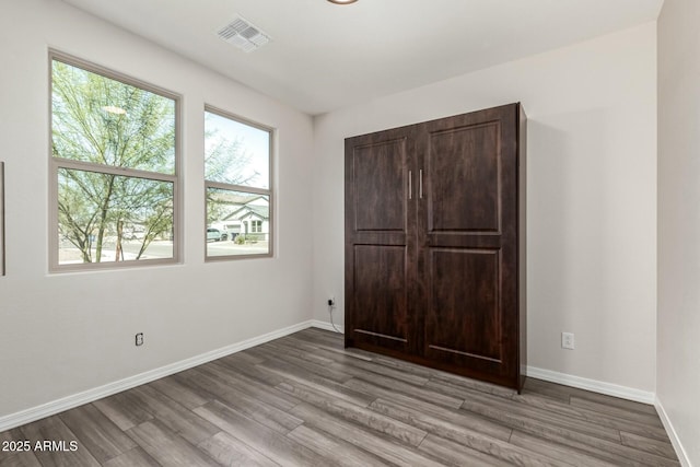 unfurnished bedroom with wood finished floors, visible vents, and baseboards