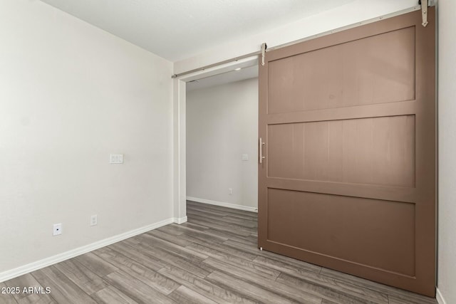 interior space with a barn door, baseboards, and wood finished floors