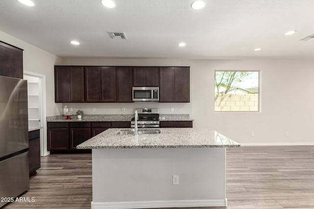 kitchen featuring visible vents, appliances with stainless steel finishes, light stone countertops, and wood finished floors