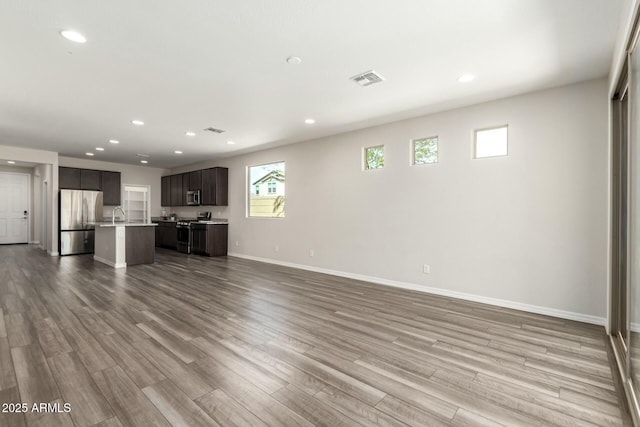 unfurnished living room with recessed lighting, visible vents, baseboards, and wood finished floors