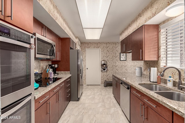 kitchen with light stone countertops, appliances with stainless steel finishes, and sink