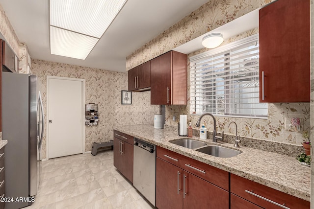 kitchen with light stone countertops, sink, and appliances with stainless steel finishes