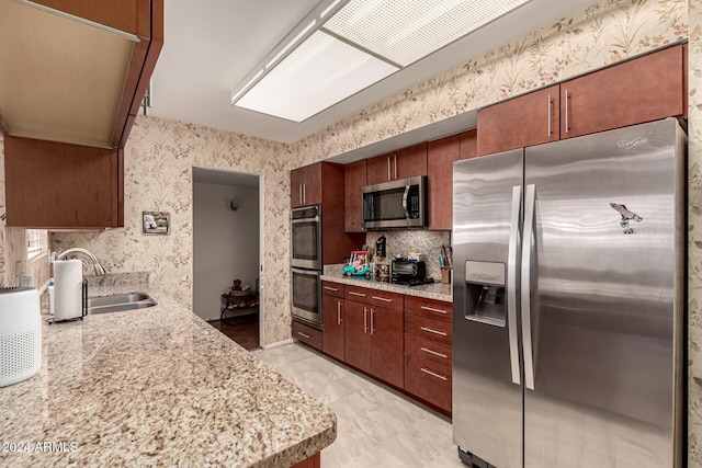 kitchen featuring light stone counters, sink, and stainless steel appliances