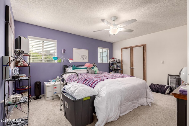 carpeted bedroom with ceiling fan and a textured ceiling