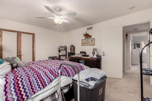 carpeted bedroom featuring ceiling fan and a textured ceiling