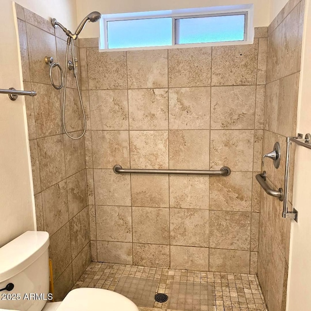 bathroom featuring tiled shower, toilet, and a wealth of natural light