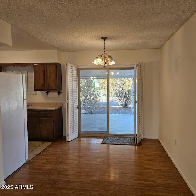 unfurnished dining area with a notable chandelier, light hardwood / wood-style floors, and a textured ceiling