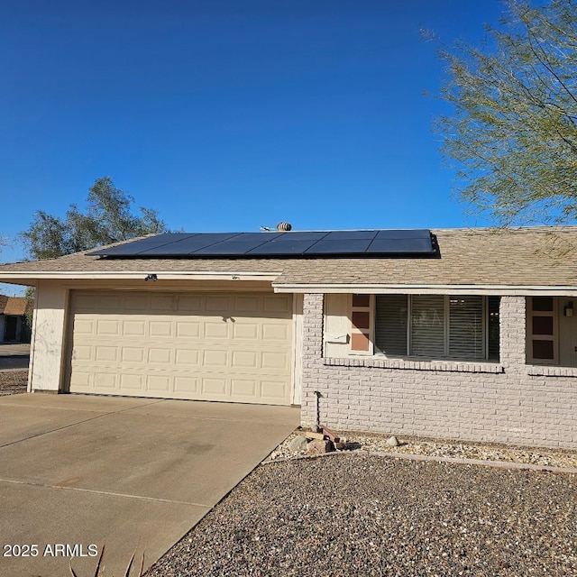 ranch-style home featuring solar panels and a garage