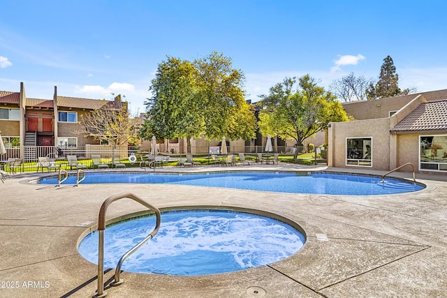 community pool featuring a community hot tub, a patio area, fence, and a residential view
