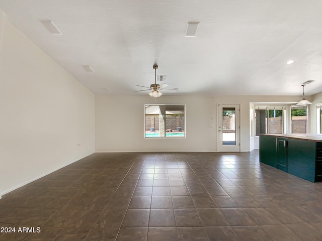 unfurnished living room featuring ceiling fan and dark tile patterned floors