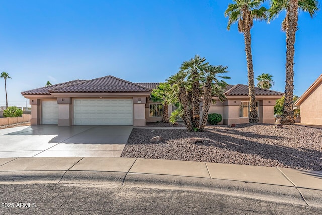 view of front of home with stucco siding, concrete driveway, a tiled roof, and a garage