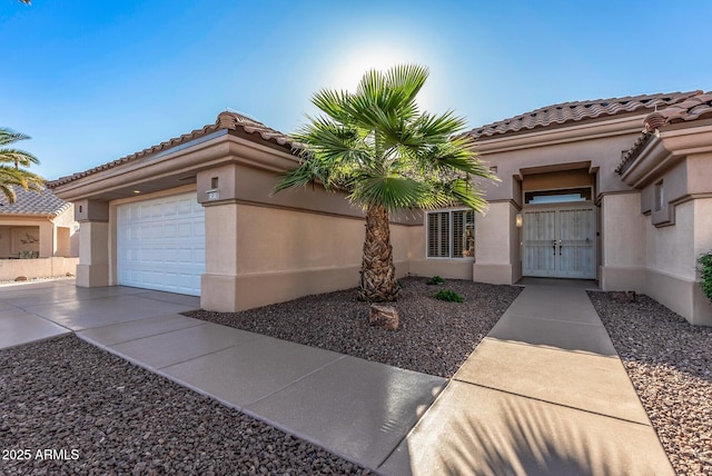 mediterranean / spanish-style house with stucco siding, driveway, a tiled roof, and a garage