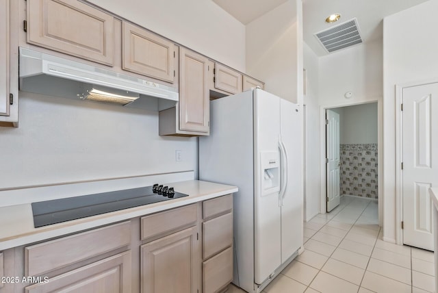 kitchen with black electric cooktop, under cabinet range hood, visible vents, light tile patterned floors, and white refrigerator with ice dispenser