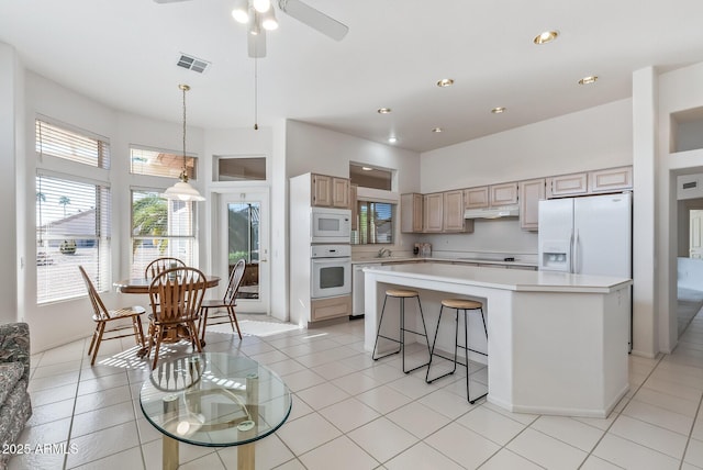 kitchen with light countertops, a wealth of natural light, visible vents, and white appliances