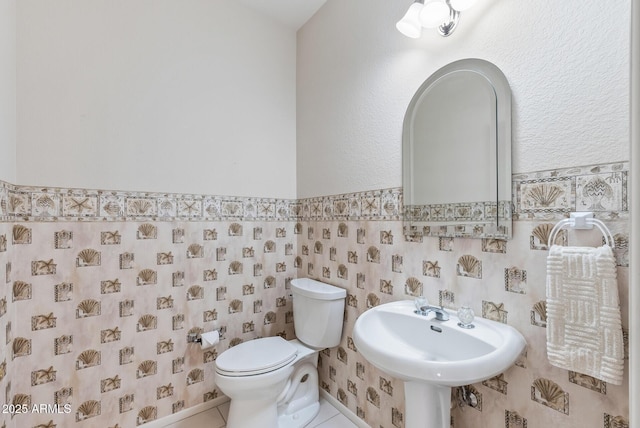 half bath featuring tile patterned floors and toilet